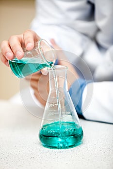 Male chemist pouring a blue liquid photo