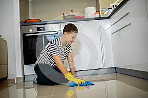 Male child cleaning the floor with the cloth.