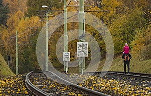 Male with child on neck on tramcar railway in autumn wet day