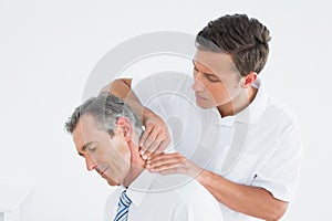 Male chiropractor massaging patients neck