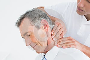 Male chiropractor massaging patients neck