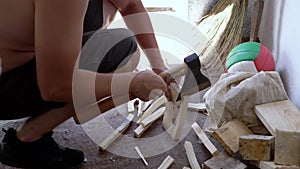 Male Chopping or Cutting Wood with a heavy ax in Garage in the Rays of Sunlight