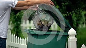 Male citizen throwing garbage in trash can, preventing littering, environment