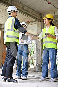 Male civil engineer shaking hands with a female construction inspector in the construction site