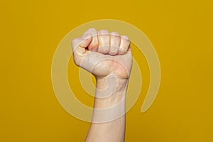 Male clenched fist, isolated on an orange background. Strong man's hand with a fist. Alpha. Protest
