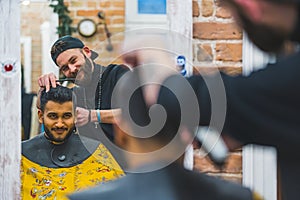 Male client and his hair stylist reflection in mirror while getting a haircut