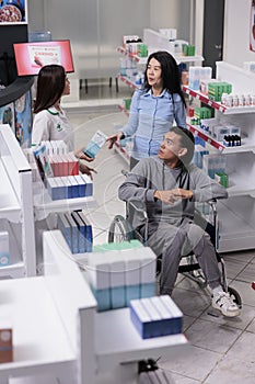 Male client in wheelchair talking to pharmacist