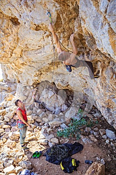 Male climber clipping rope, his partner belaying