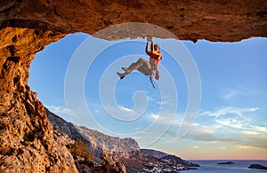 Male climber gripping on handhold while climbing in cave.