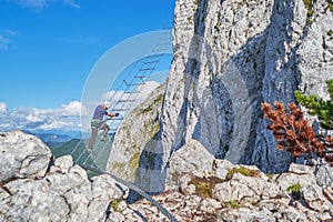 Male climber looking down from the diagonal ladder on via ferrata route called Intersport, in Donnerkogel mountains, Austria