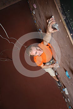 Male climber practicing rock-climbing on a rock wall indoors
