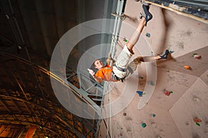 Male climber practicing rock-climbing on a rock wall indoors