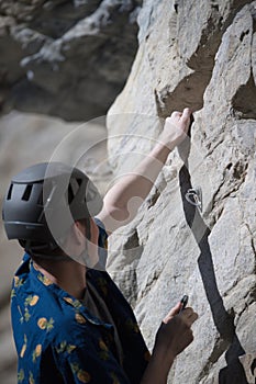 Male climber about to hook quick draw to pin on rock face photo