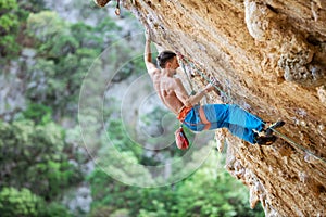 Male climber trying hard to grip small handholds on challenging route