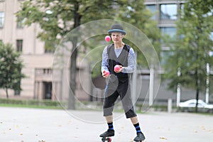 A male clown juggles with red balls