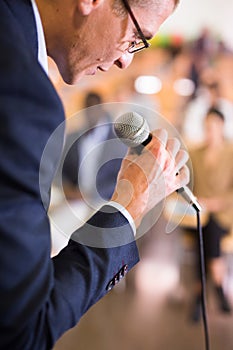 Male coach holding microphone at conference hall