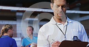 Male coach writing on clipboard in the court 4k