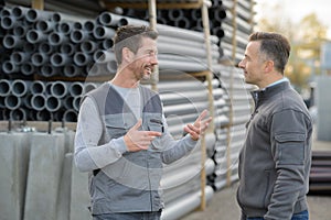 2 male coleagues chatting at pipe factory yard photo