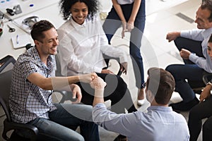 Male colleagues fist bumping at company meeting top view