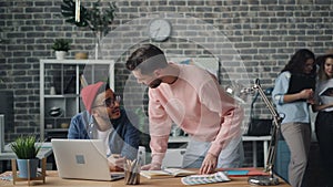 Male colleagues talking discussing project on laptop screen doing high-five