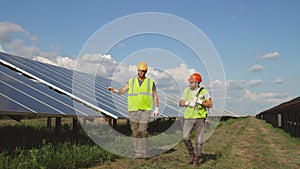 Male colleagues walking and talking on solar farm