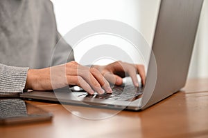 A male college student or business worker using laptop computer, typing on keyboard