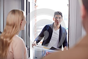 Male College Student Carrying Box Moving Into Accommodation Meeting House Mates