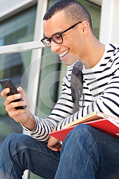 Male college student with glasses looking at mobile phone