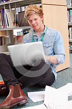 Male College Student Studying In Library With Laptop