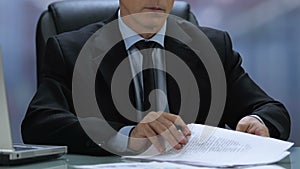 Male company director signing documents sitting office table, agreement deal