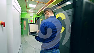 Male computer technician is walking along the server unit