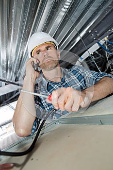 Male construction worker builder on cell phone in building ceiling