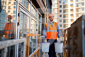 Male construction worker carrying buckets of cement