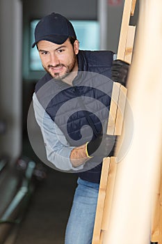 male construction worker carrying wood