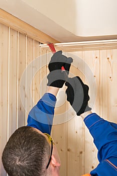 Male construction worker dismantling a wooden ceiling tearing boards