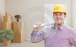 Male Construction Worker In Room With Boxes Holding Roll of Blue