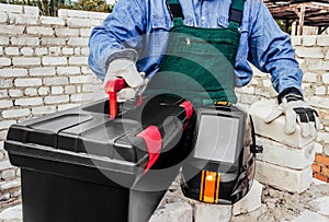 Male construction worker in uniform holding toolbox