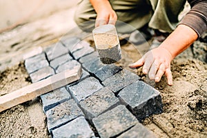 Construction worker using granite cobblestone blocks to create path or sidewalk