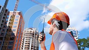 Male construction worker with walkie-talkie at construction site standing outdoors. Business, building, industry concept