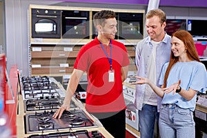 male consultor in red uniform showing hog to couple came to make purchase