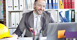 Male contractor builder greets a client on video call