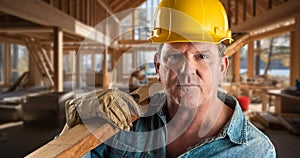 Male Contractor at a Construction Site Wearing a Hard Hat and Work Gloves Holding Lumber 2x4