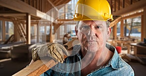 Male Contractor at a Construction Site Wearing a Hard Hat and Work Gloves Holding Lumber 2x4 photo