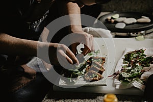 Male cook chef decorating garnishing prepared salad dish on the plate in restaurant commercial kitchen