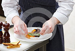 Male cook decorating dish with food