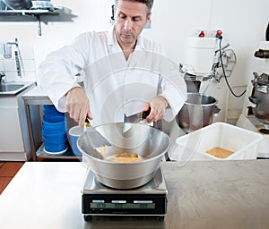 Male cook weighting honey with a spatula in commercial laboratory