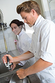 male cook wiping counter top in kitchen