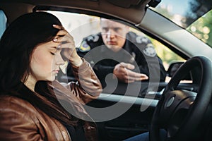 Male cop in uniform check female driver on road