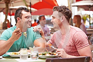 Male Couple Enjoying Lunch In Outdoor Restaurant