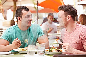 Male Couple Enjoying Lunch In Outdoor Restaurant